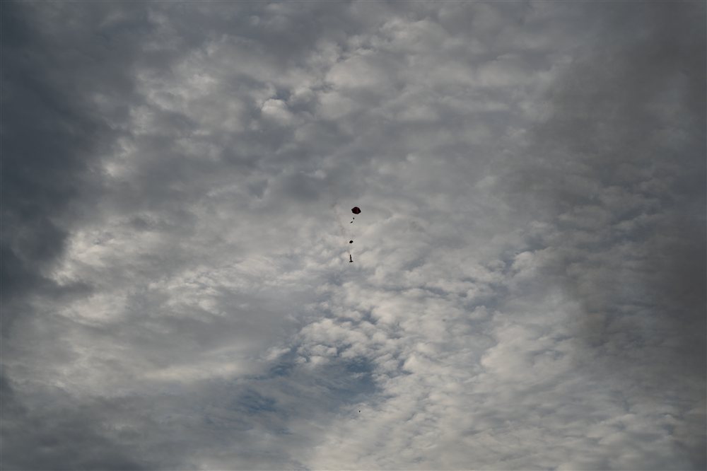 Parachute descending through a cloudy sky