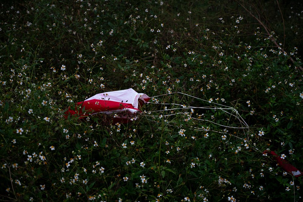 Red and white parachute lying in the grass after landing